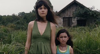 Movie still from “The Happening” (2008), directed by M. Night Shyamalan – A woman standing next to a young girl in front of a barn; Medium shot, Low angle