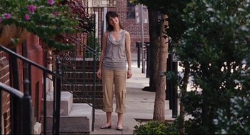 Movie still from “The Happening” (2008), directed by M. Night Shyamalan – A woman standing on a sidewalk next to a tree; Wide shot, Over the shoulder angle