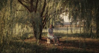 Movie still from “The Help” (2011), directed by Tate Taylor – A woman sitting on top of a wooden bench under a tree; Wide shot, High angle