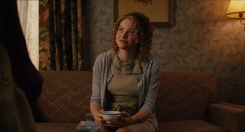 Movie still from “The Help” (2011), directed by Tate Taylor – A woman sitting on top of a couch holding a coffee cup; Medium shot, Over the shoulder angle