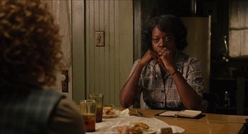 Movie still from “The Help” (2011), directed by Tate Taylor – A woman sitting at a table with a plate of food in front of her; Medium shot, Over the shoulder angle
