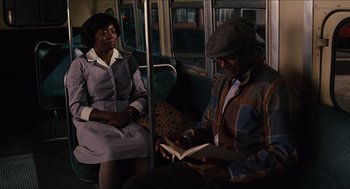 Movie still from “The Help” (2011), directed by Tate Taylor – A man and a woman sitting on a bus reading a book; Medium shot, High angle