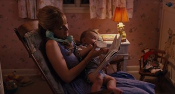 Movie still from “The Help” (2011), directed by Tate Taylor – A woman sitting in a chair with a baby reading a book; Medium shot, High angle