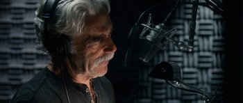 Movie still from “The Hero” (2017), directed by Brett Haley – An older man with white hair and a white beard is in front of a microphone in a recording studio; Close Up shot, Low angle