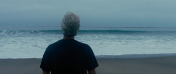 Movie still from “The Hero” (2017), directed by Brett Haley – A man standing on the beach looking out at the ocean; Medium shot, Low angle