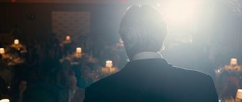 Movie still from “The Hero” (2017), directed by Brett Haley – A man wearing a suit and tie standing in front of candles; Close Up shot, Over the shoulder angle