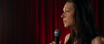 Movie still from “The Hero” (2017), directed by Brett Haley – A woman is holding a microphone up to her face; Close Up shot, Over the shoulder angle