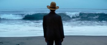 Movie still from “The Hero” (2017), directed by Brett Haley – A man wearing a cowboy hat standing in front of the ocean; Wide shot, Low angle