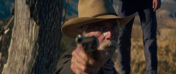 Movie still from “The Hero” (2017), directed by Brett Haley – An old man with a mustache and a hat is holding a gun; Close Up shot, Over the shoulder angle