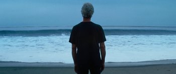 Movie still from “The Hero” (2017), directed by Brett Haley – A man standing on the beach looking out at the ocean; Medium shot, Low angle