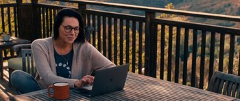 Movie still from “The Hero” (2017), directed by Brett Haley – A woman sitting at a table using a laptop computer; Medium shot, Over the shoulder angle