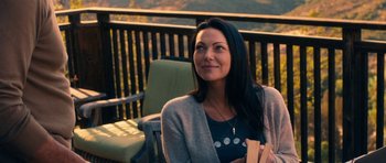 Movie still from “The Hero” (2017), directed by Brett Haley – A woman sitting on top of a chair holding a book; Medium shot, Over the shoulder angle