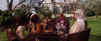 Movie still from “Practical Magic” (1998), directed by Griffin Dunne – A group of people sitting at a table with food on top of it; Wide shot, High angle