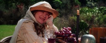 Movie still from “Practical Magic” (1998), directed by Griffin Dunne – A woman sitting at a table with grapes on the table; Close Up shot, High angle