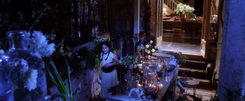 Movie still from “Practical Magic” (1998), directed by Griffin Dunne – A young girl standing in front of a table filled with vases and candles; Wide shot, High angle
