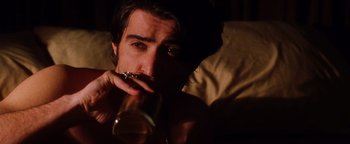 Movie still from “Practical Magic” (1998), directed by Griffin Dunne – A man drinking a glass of beer while sitting on a couch; Close Up shot, Low angle