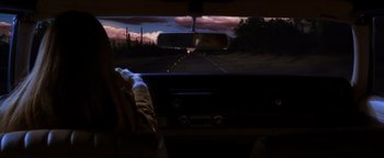 Movie still from “Practical Magic” (1998), directed by Griffin Dunne – A view of a road from a car's dashboard at night; Wide shot, Over the shoulder angle