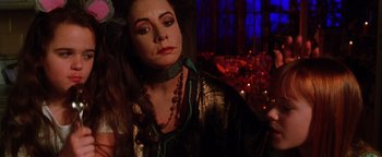 Movie still from “Practical Magic” (1998), directed by Griffin Dunne – A woman wearing a green necklace and a gold jacket; Close Up shot, Over the shoulder angle