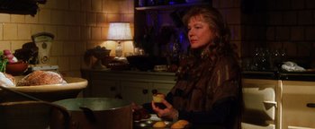 Movie still from “Practical Magic” (1998), directed by Griffin Dunne – A woman sitting at a table holding a cupcake; Close Up shot, Over the shoulder angle