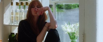 Movie still from “Practical Magic” (1998), directed by Griffin Dunne – A woman sitting in front of a window holding a cell phone; Medium shot, Low angle