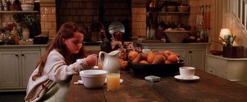 Movie still from “Practical Magic” (1998), directed by Griffin Dunne – A little girl sitting at a table drinking orange juice; Medium shot, High angle