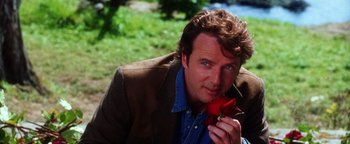 Movie still from “Practical Magic” (1998), directed by Griffin Dunne – A person holding a flower near a body of water; Close Up shot, Over the shoulder angle
