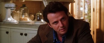 Movie still from “Practical Magic” (1998), directed by Griffin Dunne – A person wearing a suit and tie; Close Up shot, Over the shoulder angle