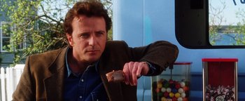 Movie still from “Practical Magic” (1998), directed by Griffin Dunne – A man holding a piece of food in his hand; Close Up shot, Over the shoulder angle