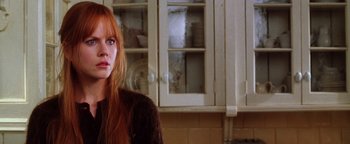 Movie still from “Practical Magic” (1998), directed by Griffin Dunne – A woman with red hair standing in front of a cabinet; Close Up shot, Low angle