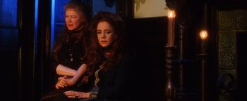 Movie still from “Practical Magic” (1998), directed by Griffin Dunne – A woman sitting next to a candle in a dark room; Medium shot, High angle