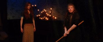 Movie still from “Practical Magic” (1998), directed by Griffin Dunne – Two women in a dark room with candles in the background; Medium shot, High angle