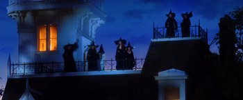 Movie still from “Practical Magic” (1998), directed by Griffin Dunne – A group of people dressed as witches standing on a balcony; Wide shot, Low angle