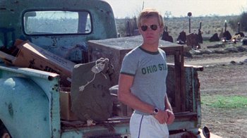 Movie still from “The Hills Have Eyes” (1977), directed by Wes Craven – A man standing in front of an old rusted truck; Medium shot, Low angle