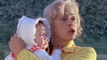Movie still from “The Hills Have Eyes” (1977), directed by Wes Craven – An older woman holding a baby in her arms; Close Up shot, Low angle