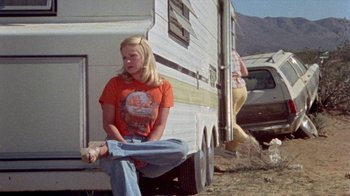 Movie still from “The Hills Have Eyes” (1977), directed by Wes Craven – A woman sitting in front of an rv with another woman standing next to it; Wide shot, Low angle