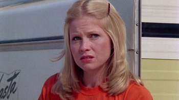 Movie still from “The Hills Have Eyes” (1977), directed by Wes Craven – A woman in an orange shirt is looking at the camera; Close Up shot, Low angle