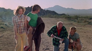 Movie still from “The Hills Have Eyes” (1977), directed by Wes Craven – A group of people standing on top of a dirt field; Wide shot, High angle