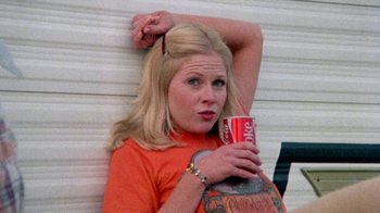 Movie still from “The Hills Have Eyes” (1977), directed by Wes Craven – A woman holding a can of coke while sitting on the ground; Close Up shot, Low angle