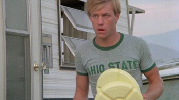 Movie still from “The Hills Have Eyes” (1977), directed by Wes Craven – A man holding a frisbee in front of a house; Close Up shot, Low angle