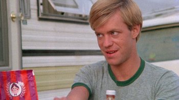 Movie still from “The Hills Have Eyes” (1977), directed by Wes Craven – A young man holding a bottle of soda; Close Up shot, Over the shoulder angle