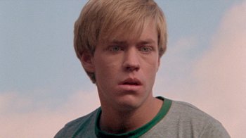Movie still from “The Hills Have Eyes” (1977), directed by Wes Craven – A person wearing a green shirt; Close Up shot, Low angle