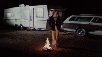 Movie still from “The Hills Have Eyes” (1977), directed by Wes Craven – A man standing in front of a fire in the dark; Wide shot, Low angle