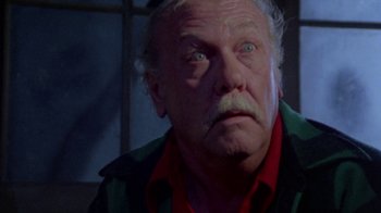 Movie still from “The Hills Have Eyes” (1977), directed by Wes Craven – An old man with a beard and a mustache looking at the camera; Close Up shot, Low angle