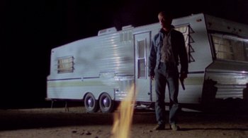 Movie still from “The Hills Have Eyes” (1977), directed by Wes Craven – A man standing in front of an rv with a fire in front of him; Wide shot, Low angle