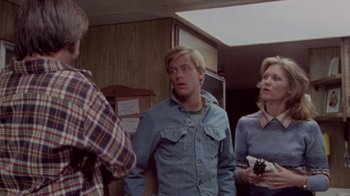 Movie still from “The Hills Have Eyes” (1977), directed by Wes Craven – A group of people standing in a room talking to each other; Medium shot, Over the shoulder angle