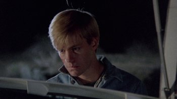 Movie still from “The Hills Have Eyes” (1977), directed by Wes Craven – A man with blonde hair is looking at a computer screen; Close Up shot, Low angle