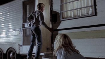 Movie still from “The Hills Have Eyes” (1977), directed by Wes Craven – A man and a woman standing in front of an open door; Wide shot, Low angle