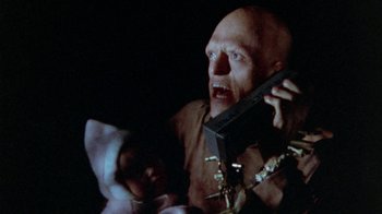 Movie still from “The Hills Have Eyes” (1977), directed by Wes Craven – A man holding a nintendo wii game controller in his hand; Close Up shot, Low angle