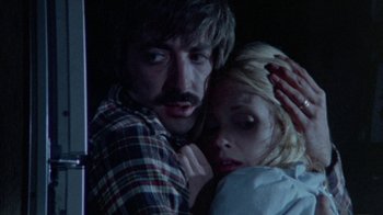 Movie still from “The Hills Have Eyes” (1977), directed by Wes Craven – A man and a woman embracing each other in a dark room; Close Up shot, Low angle