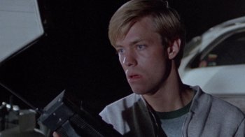 Movie still from “The Hills Have Eyes” (1977), directed by Wes Craven – A young man holding a gun in a dark room; Close Up shot, Low angle